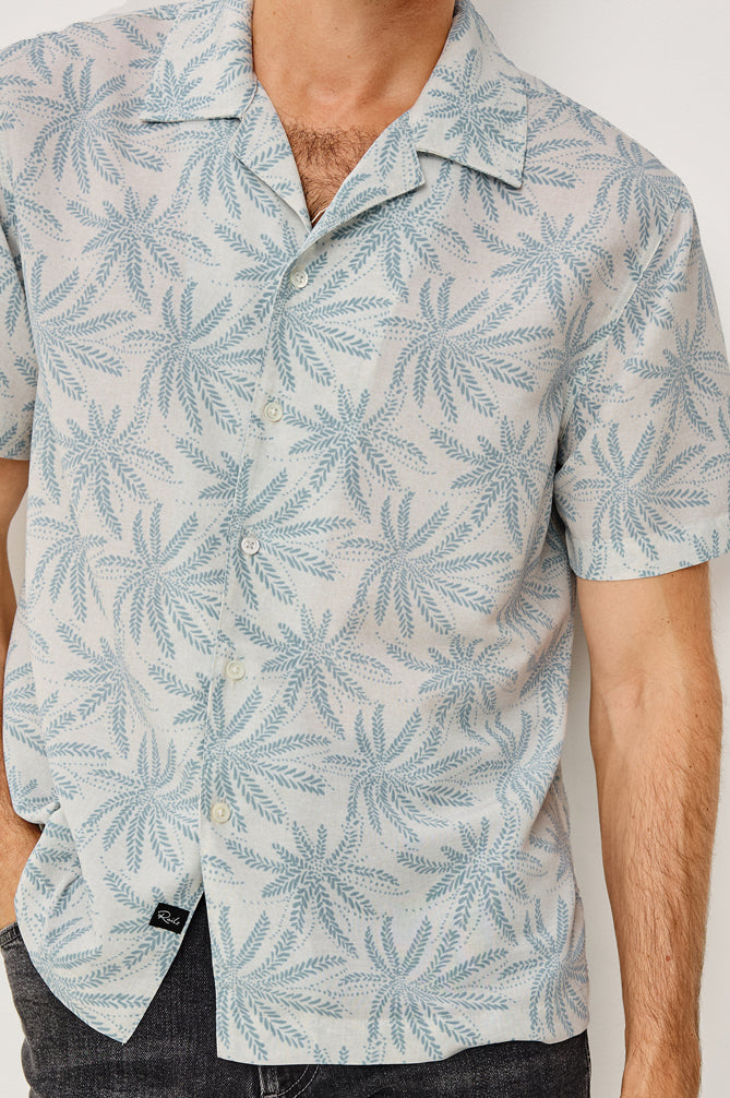 Man wearing a light blue patterned shirt with a plain background