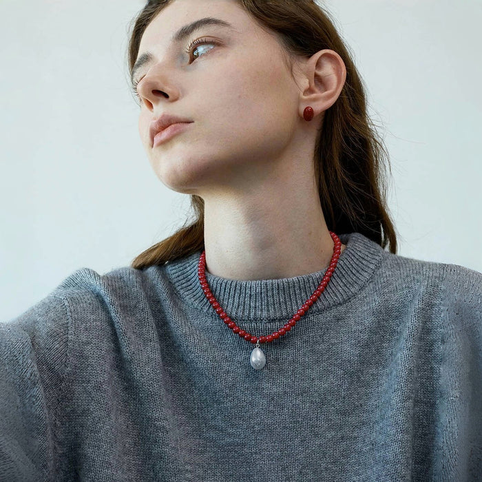 Side view of model styling the red rose dew necklace, sophisticated feminine accessory