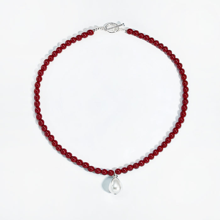 Flat lay of red rose dew necklace showing artificial pearl drop and toggle clasp