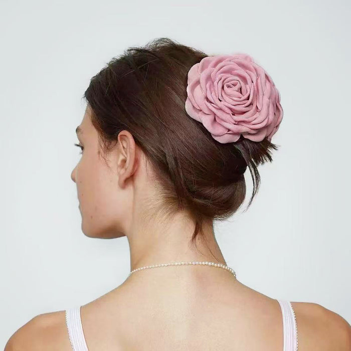 Back view of a model with an elegant updo secured by a dusty pink rose hair claw.