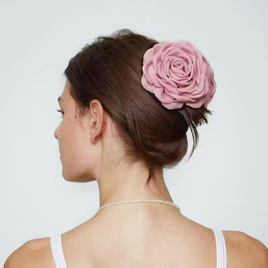 Back view of a model with an elegant updo secured by a dusty pink rose hair claw.
