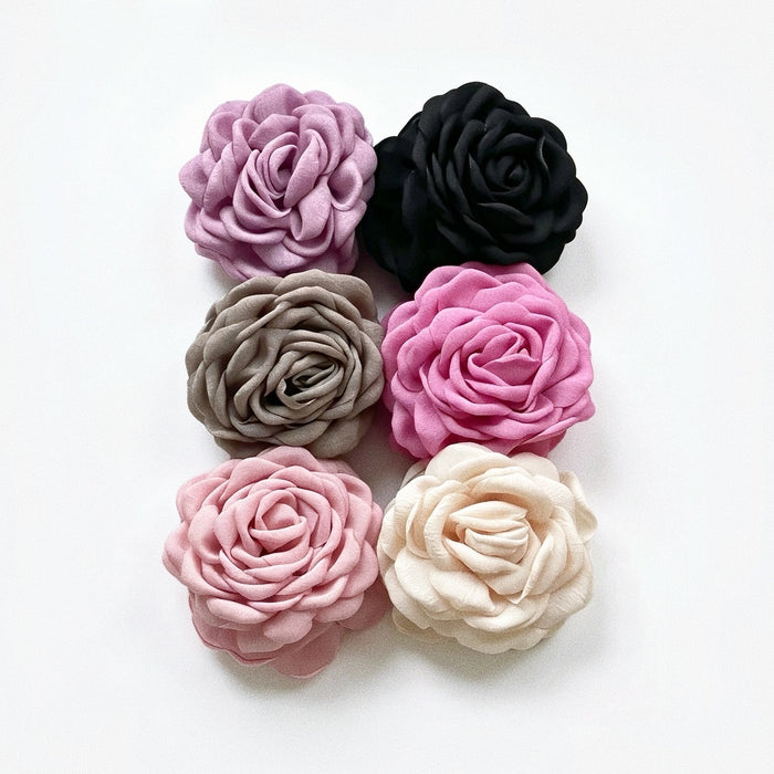 Group shot showing various fabric rose hair claw clips including dusty pink, greige, red, mauve, black and beige.