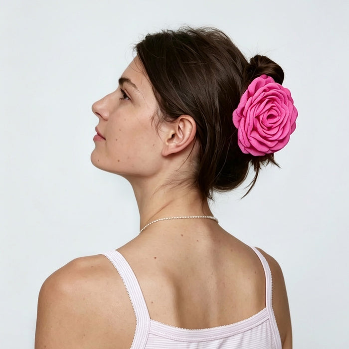 Back view of a model styling a vibrant magenta pink rose hair claw in a bun updo.