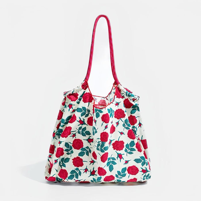Front view of White polyester tote bag with red rose print, green leaves, and two red grab straps.