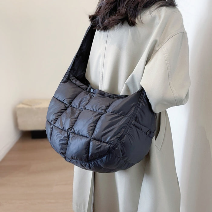 Model carring a black puffy crossbody bag as crossbody; minimalist and functional quilted bag for urban chic.