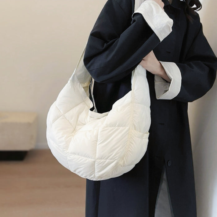 Model styling a white puffy sling bag over a black coat; high-contrast comfort aesthetic fashion accessory.