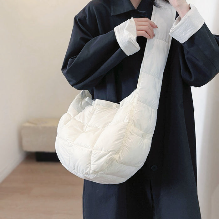 Mode carring a white padded hobo bag as crossbody; highlighting the air-puffed quilting texture and clean color.