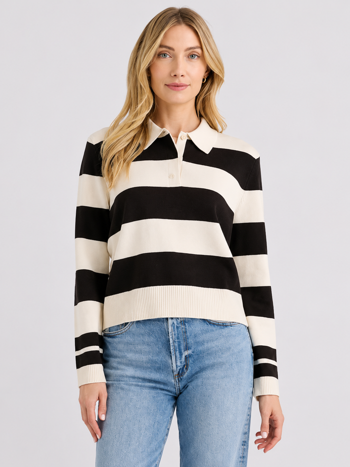 Woman wearing a black and white striped sweater with blue jeans on a light gray background