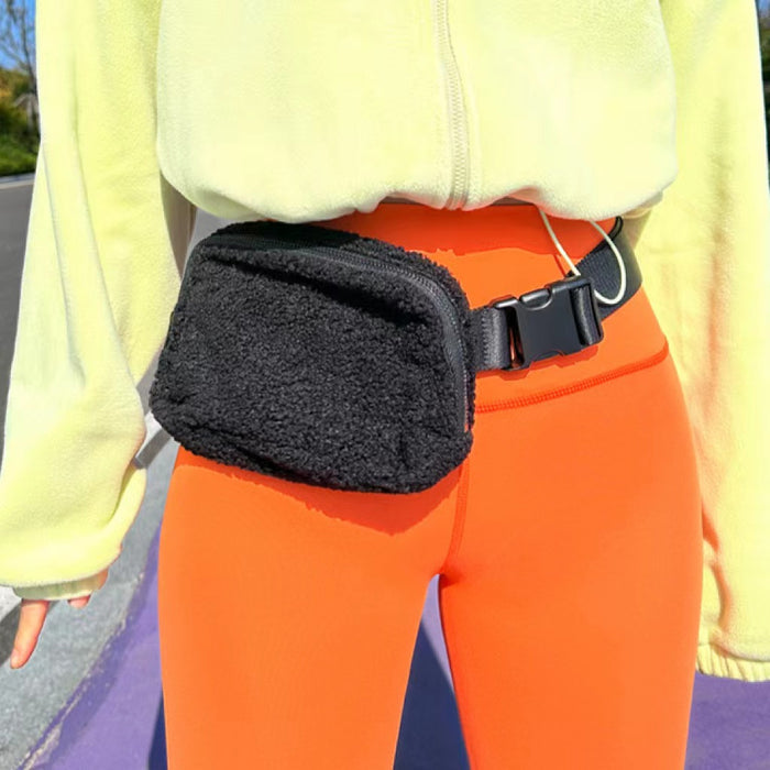 Close-up of black sherpa fanny pack on vibrant orange pants; street style plush bag with adjustable strap.
