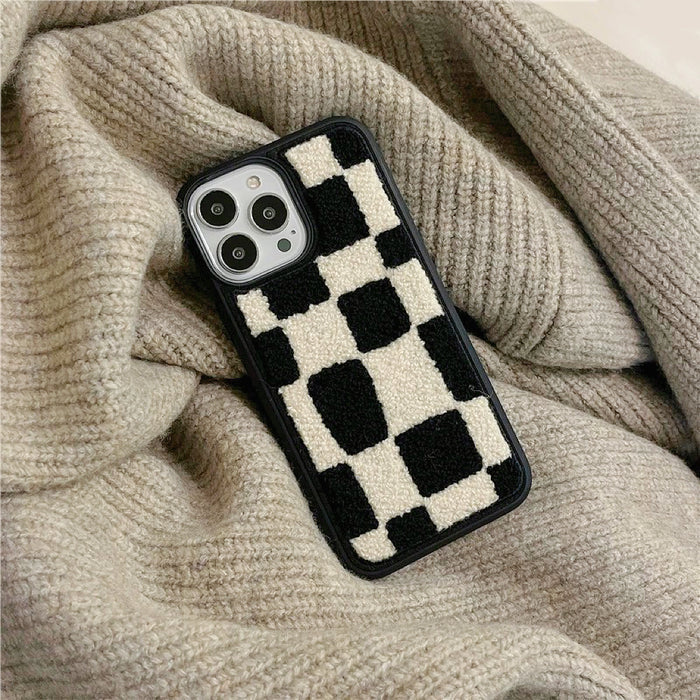 Sherpa checkered case on a beige knitted background. Cozy lifestyle flatlay for winter fashion.