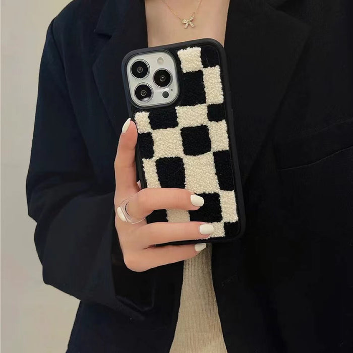 Model holding Sherpa Checkered Case in Black. Classic plush checkered motif on a protective base.