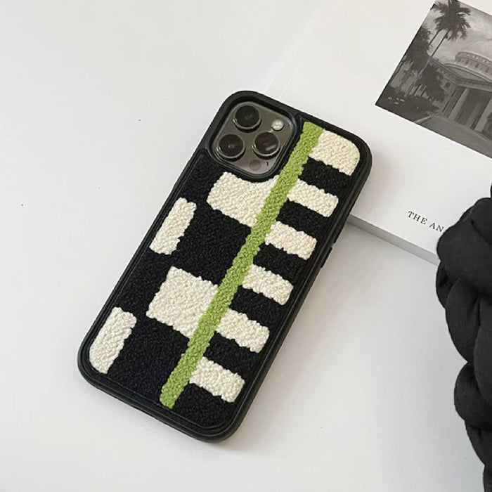 Sherpa Green Stripe case resting on a white surface next to an aesthetic magazine.