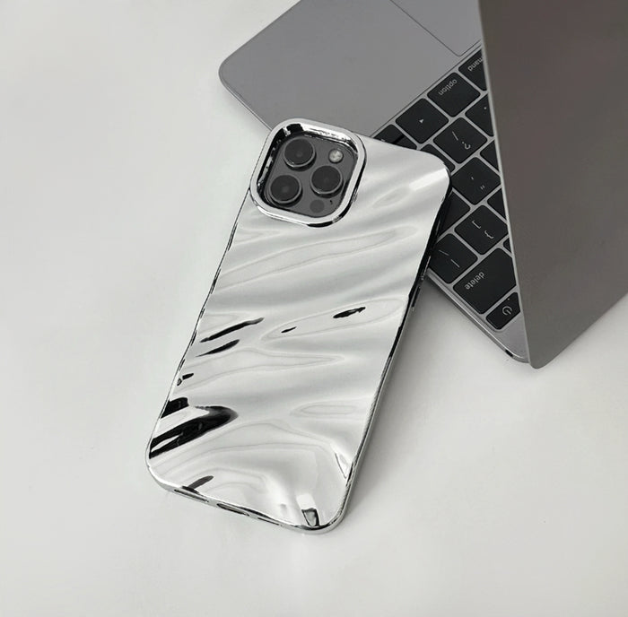 Silver glossy wave case with a reflective fluid design, shown next to a laptop.