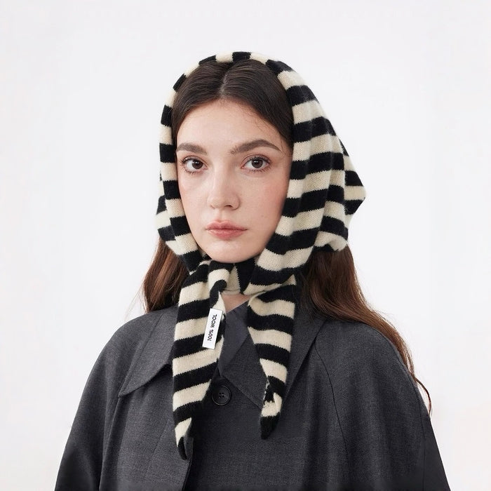 Model wearing a black and white striped 100% wool triangular scarf, tied under her chin.
