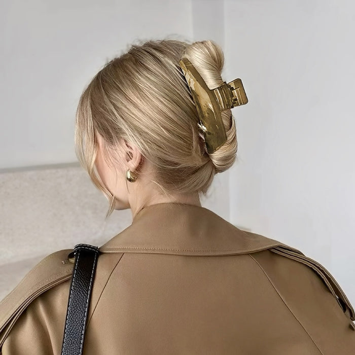 Blonde hair styled in a bun with a large, sleek curved hair claw in olive green.