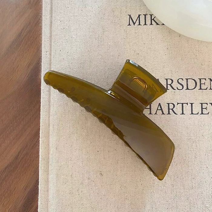 Angled view of Sleek Curved Hair Claw in olive green, ideal for quick updos and ponytails.