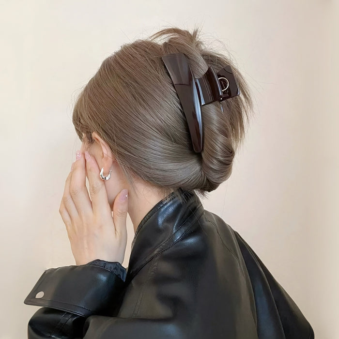 Model wearing a Sleek Curved Hair Claw in dark brown , easy for workdays and special occasions.