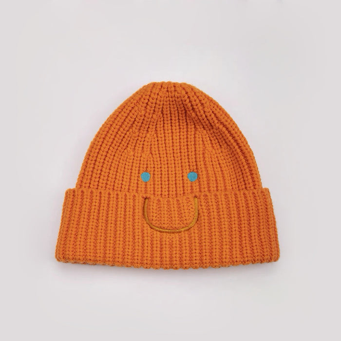 Front view of Smiley Ribbed Knit Beanie in orange. Vibrant fall color with a whimsical smile embroidery.