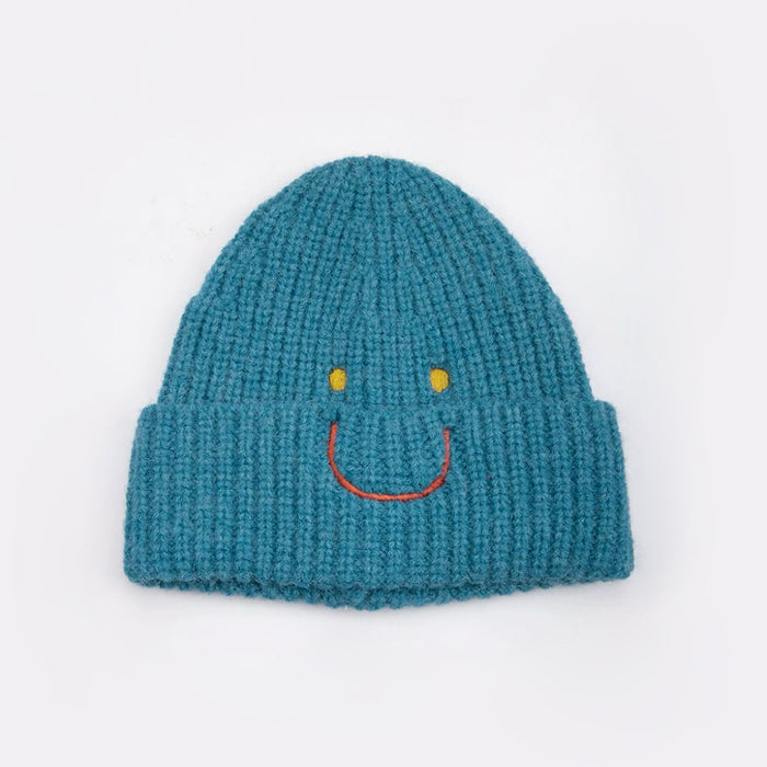 Front view of Smiley Ribbed Knit Beanie in peacock blue. Durable knit frame with an artistic smiley detail.