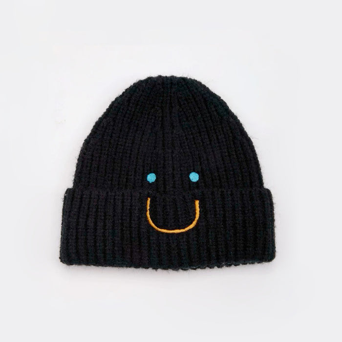 Front view of Smiley Ribbed Knit Beanie in black. Minimalist dark tone paired with a playful smile motif.