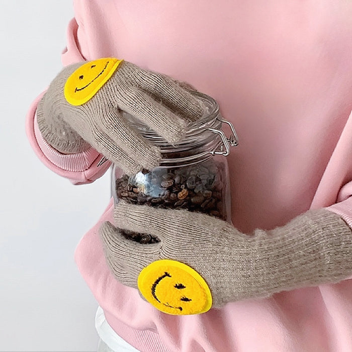 Khaki smiling round face gloves with plush knit and smile patch, flat lay; warm and playful for cold days.