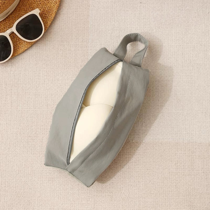 Grey Soft Hue organizer bag partially open with round bottle; compact zip pouch with handle for makeup or toiletries.