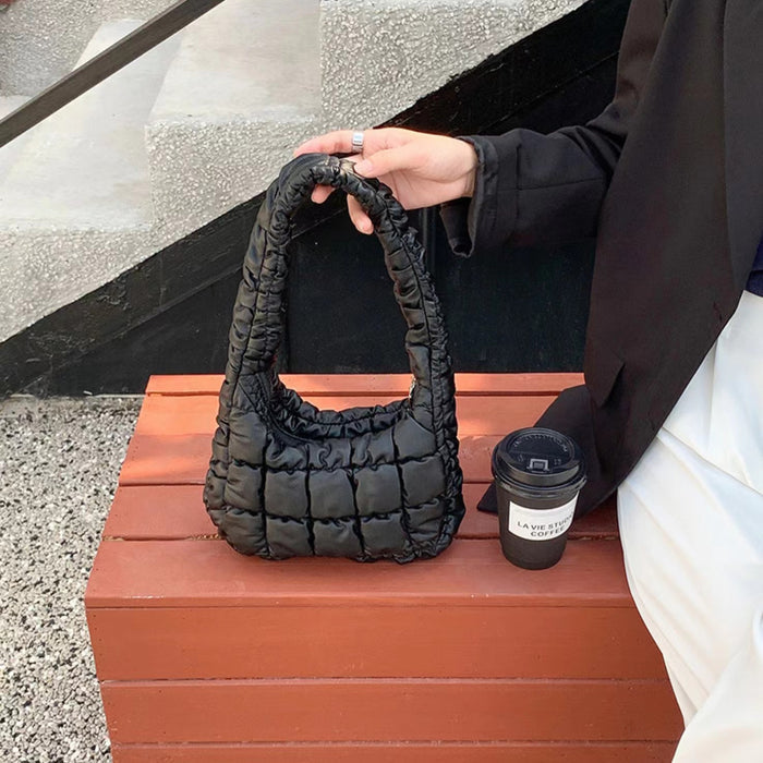 Model carrying a black Soft Leather Puffer Shoulder Bag handheld, great for daily carry and travel.