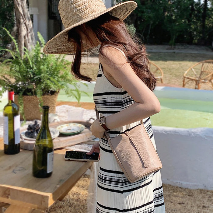 Model carrying the khaki leather crossbody bag for a refined urban look.