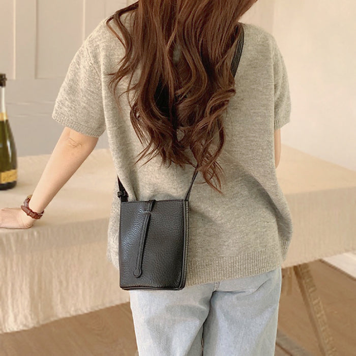 Side profile showing the structured shape of the black lychee leather bag.