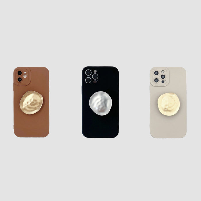Three silicone iPhone cases in brown, black, and beige with integrated gold or silver metallic kickstands.