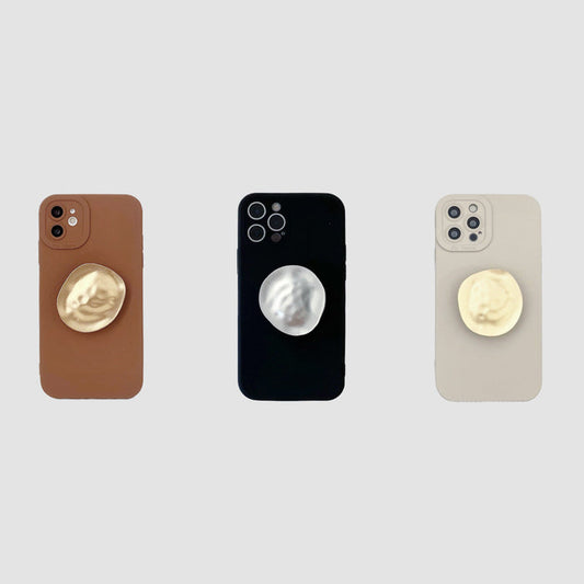 Three silicone iPhone cases in brown, black, and beige with integrated gold or silver metallic kickstands.