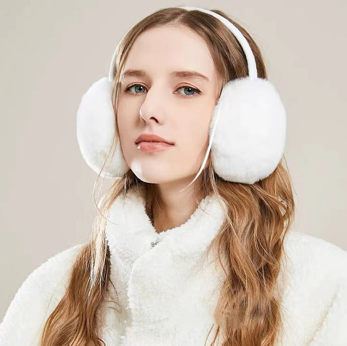 Model wearing white plush earmuffs; elegant winter accessory for outdoor ice skating and travel.