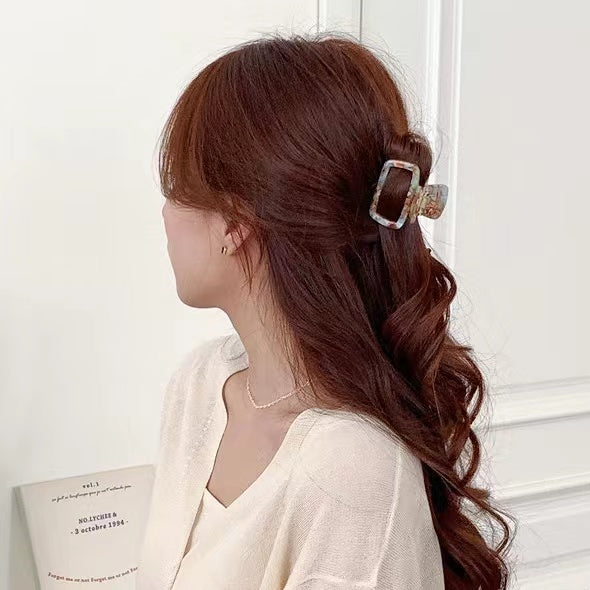 Model wearing a cyan marbled square claw for a half-up style, chic accessory for long wavy hair.