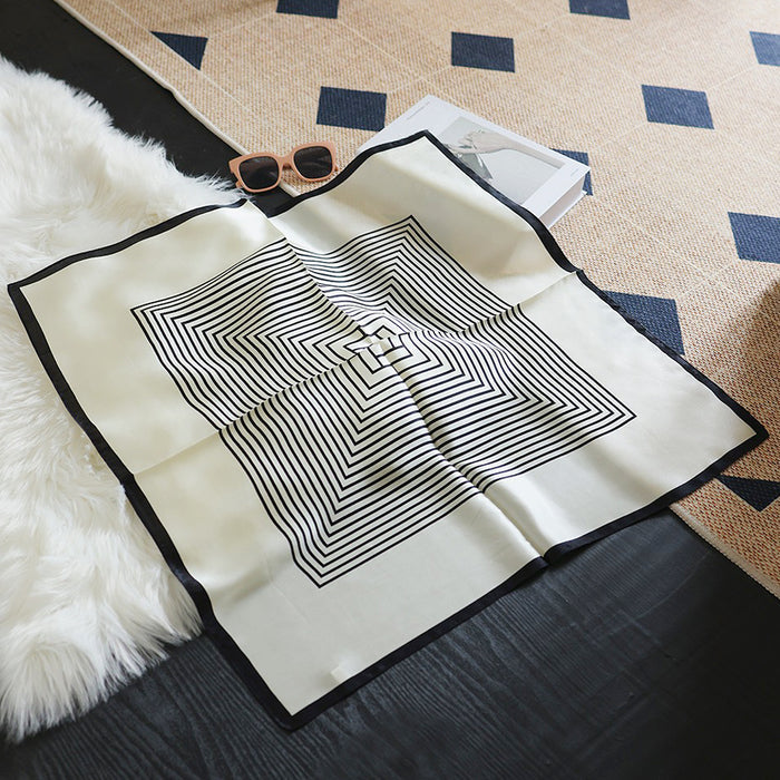 Full view of the black and white square pattern silk scarf laid flat.