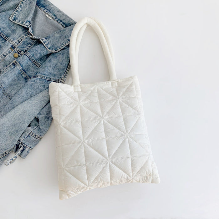 Close-up of White polyester quilted shoulder bag with a geometric Starburst pattern, next to a denim jacket Starburst.
