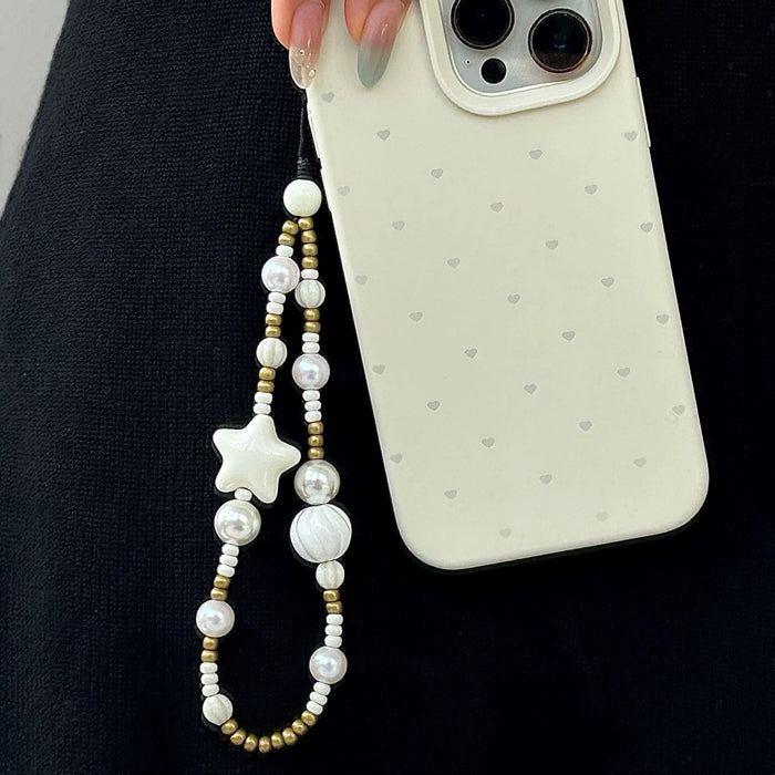Close-up of Starry Pearl Delight Phone Charm hanging on a phone case, ideal for travel and daily use.