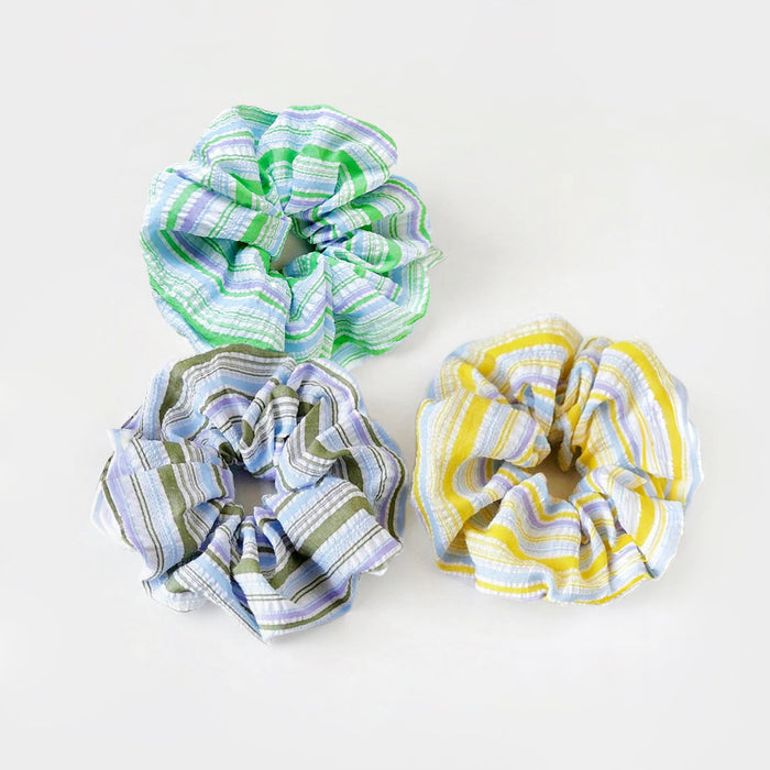 Three polyester scrunchies with colorful stripe patterns: green, blue, and yellow.