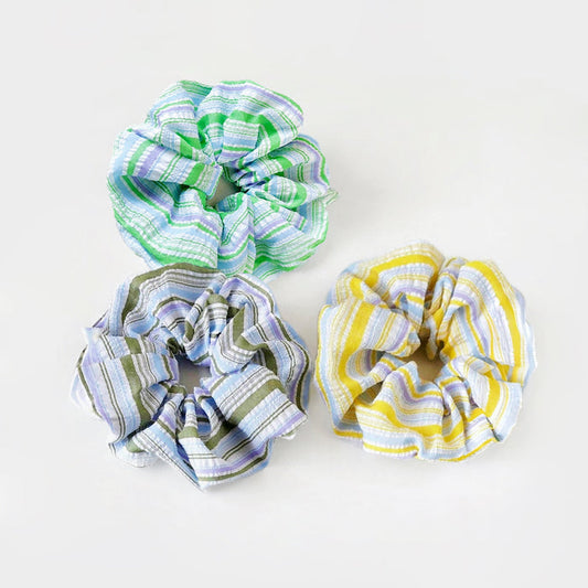 Three polyester scrunchies with colorful stripe patterns: green, blue, and yellow.
