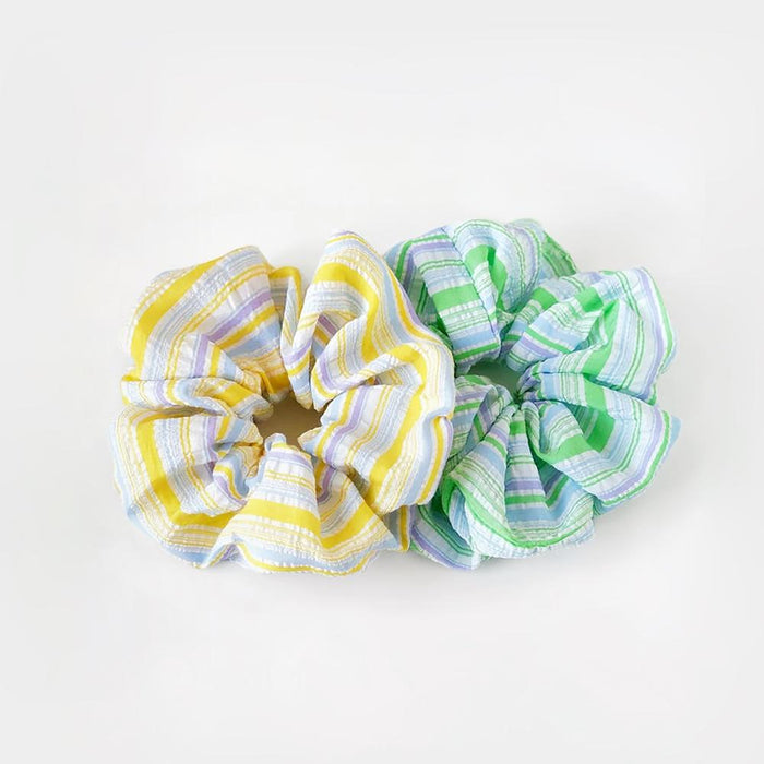 Angled view of two Stripe Scrunchies shown together, yellow and green.