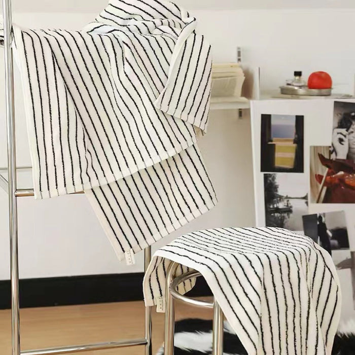 White cotton stripe face towel and bath towel set, hanging and folded on chrome racks.