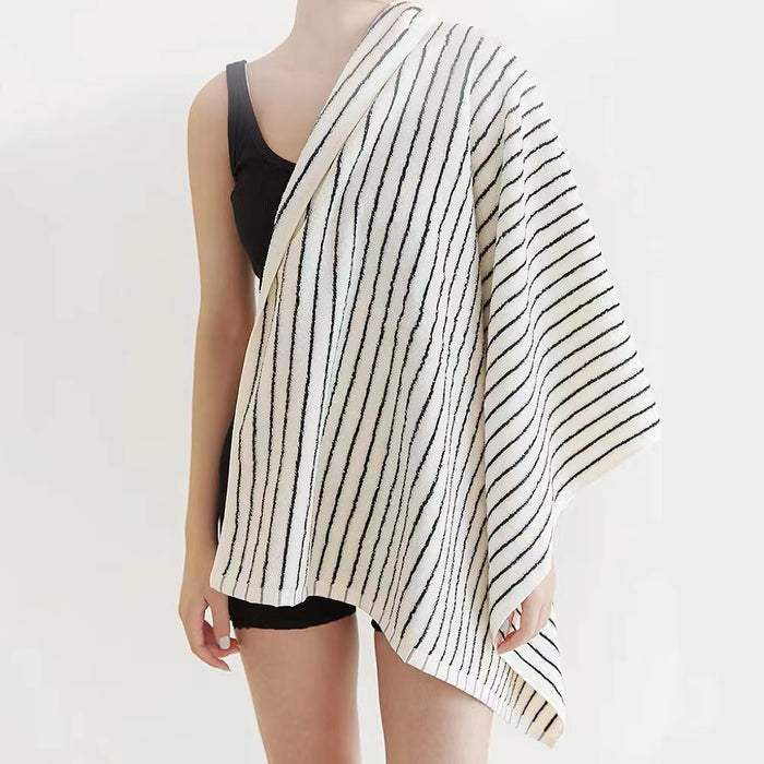 Model having a white-black striped bath towel draped over her shoulder.