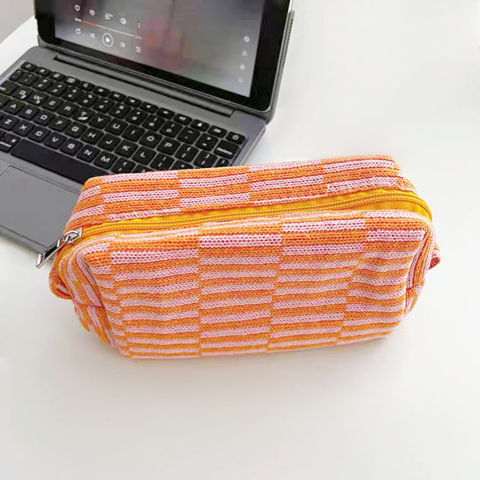 Front view of orange striped knitted makeup bag, easy to pack for trips.