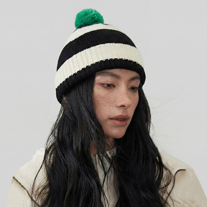 Model wearing the black and white striped beanie with a green pompom.