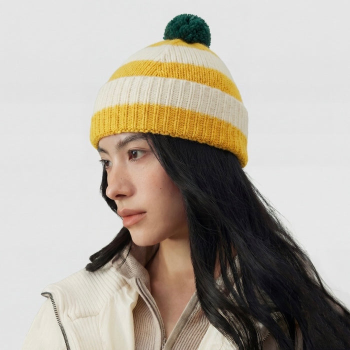 Model wearing the yellow and white striped beanie with a green pompom.