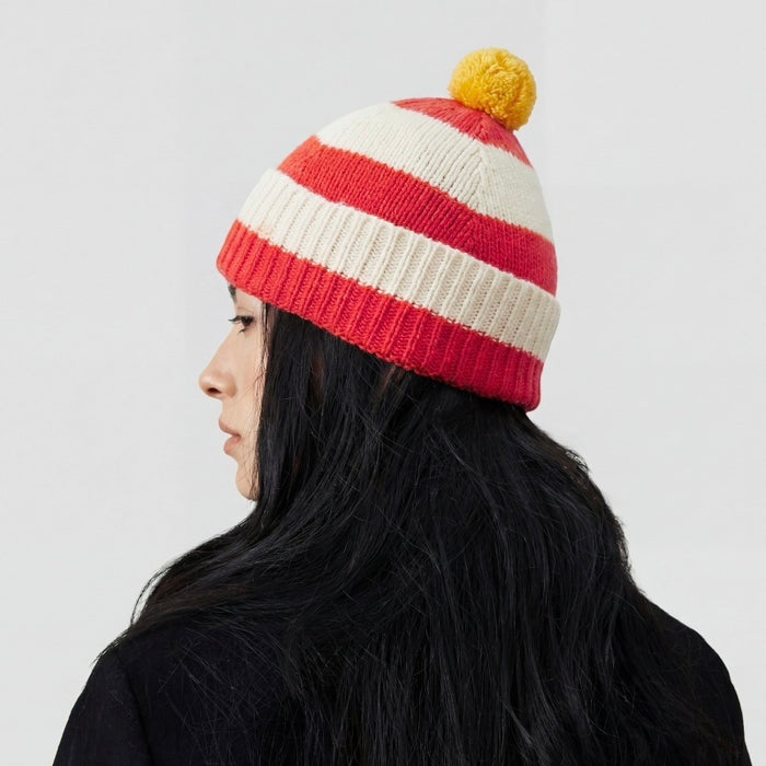 Model wearing the red and white striped beanie with a yellow pompom.