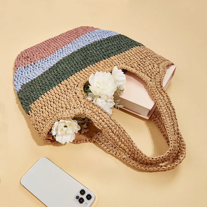 Stripe rattan straw bag with pink, blue, green, and natural stripes, holding white flowers and a book.