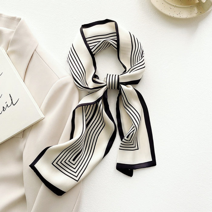 Front view of tied Black and white striped satin skinny scarf on a light blazer in wine, great for office layering.