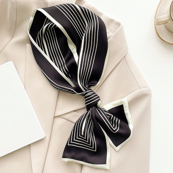 Flat lay of tied Stripe Satin Skinny Scarf in black, great for office layering and commuting.
