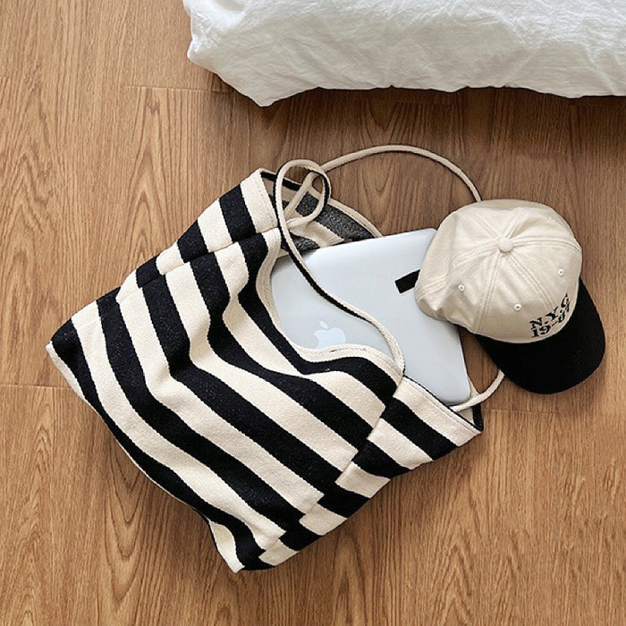 Close-up of Black and cream stripe textured canvas tote bag with a laptop and baseball cap inside, great for everyday.