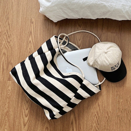 Close-up of Black and cream stripe textured canvas tote bag with a laptop and baseball cap inside, great for everyday.